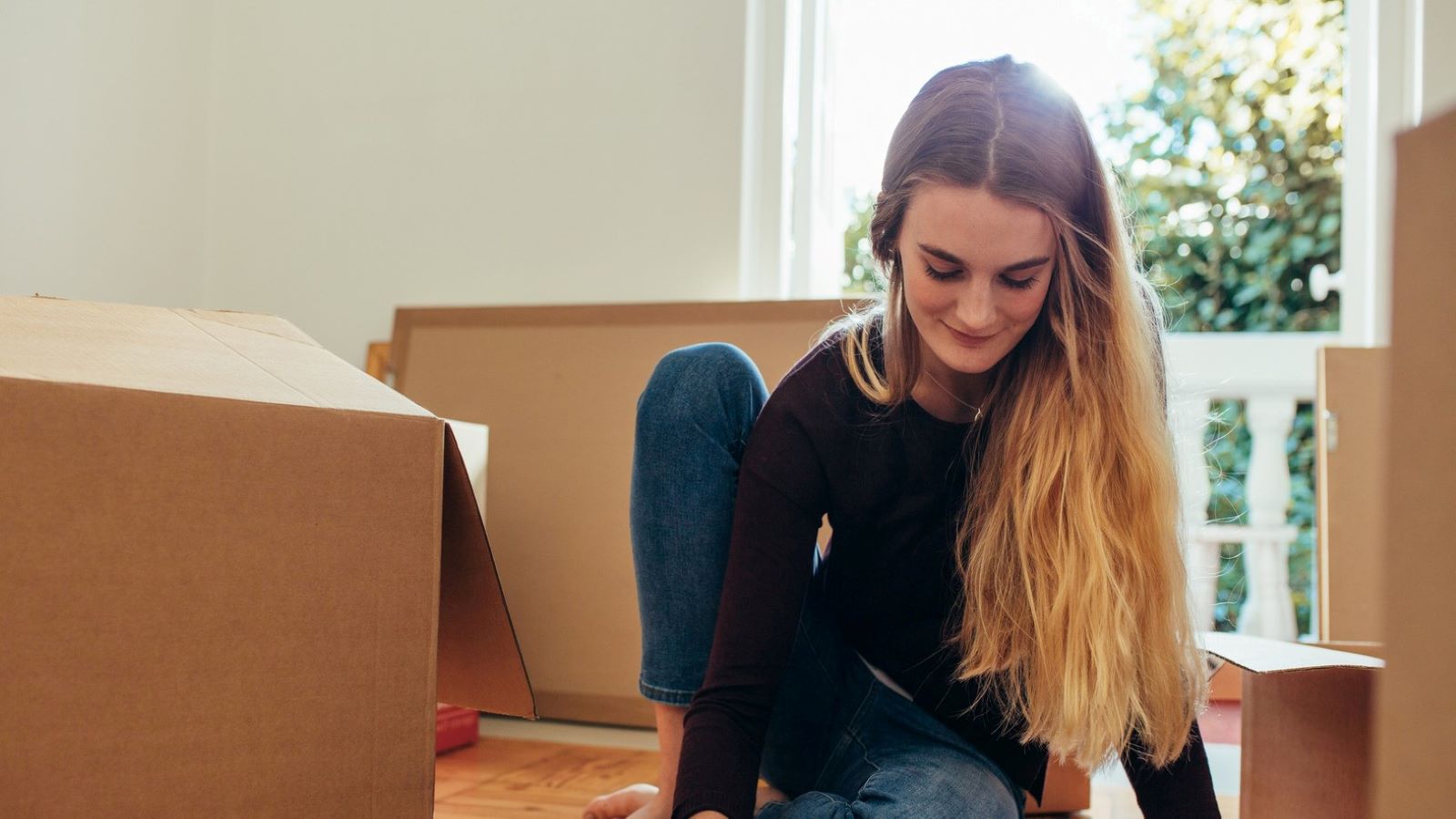 Woman sitting surrounded by moving boxes.
