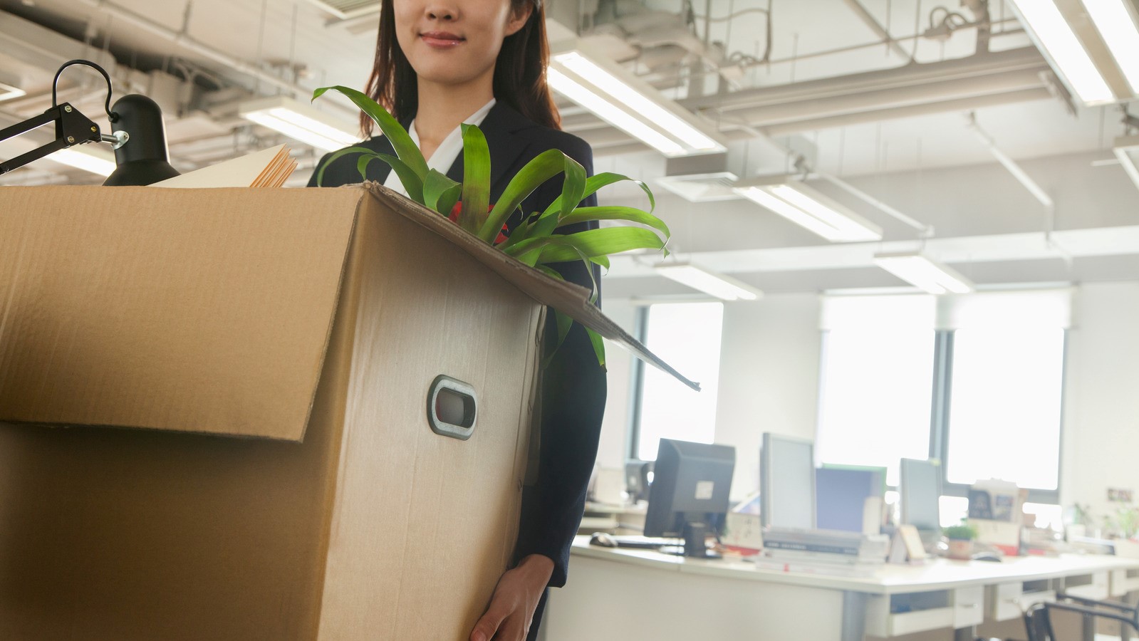 Woman carrying box in office setting