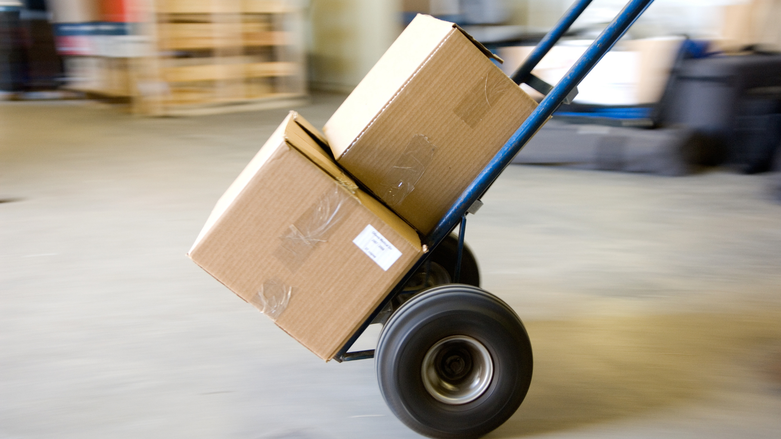 Image of a dolly transporting two moving boxes in an empty garage space.
